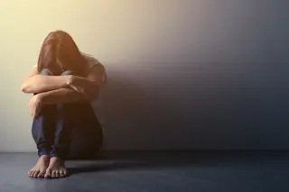 young woman with hikikomori syndrome sitting alone on the floor in a dark room