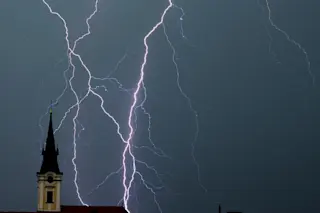 Lightning bolts striking behind a church steeple
