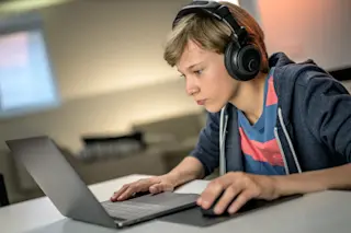Child-with-headphones-sitting-at-laptop