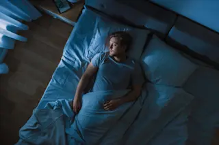 man sleeping in bed alone - shutterstock