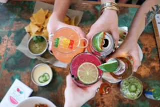 Four hands cheersing four different alcoholic beverages - Shutterstock