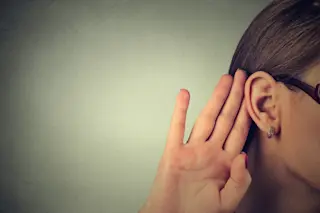 Woman with hand up to her ear, listening hearing - Shutterstock