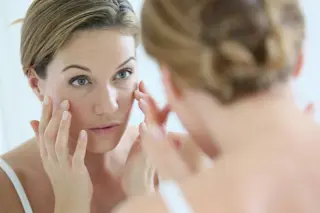 woman looking in mirror wrinkles - shutterstock