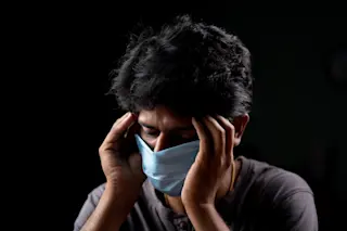 man has a headache after his covid-19 vaccine - shutterstock