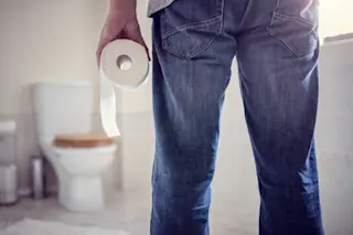 man facing toilet holding toilet paper in bathroom - shutterstock 644195584