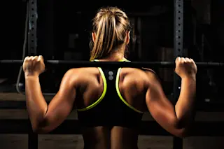 woman is lifting weights at the gym - shutterstock 524428588