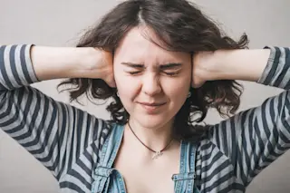 young woman covering her ears - shutterstock