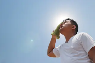 Young man standing outside in the sun with heat stroke