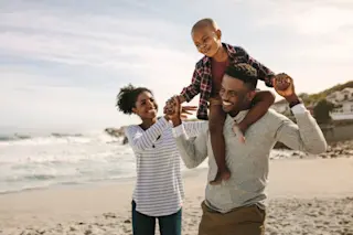 small family at the beach - shutterstock 1301311915