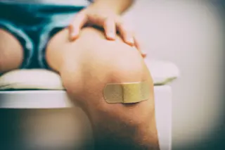 child sitting down with a bandaid on knee - shutterstock 212590312