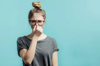 woman wearing glasses holding her nose from a smelly fart