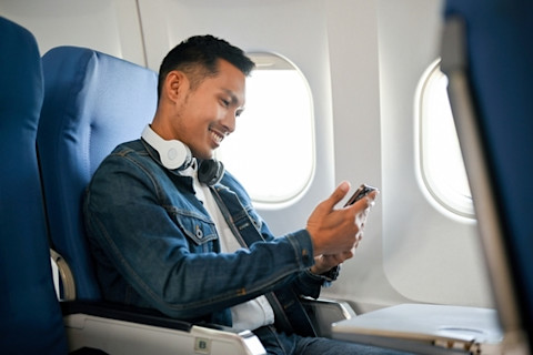 Airplane passenger using his smartphone during the flight.