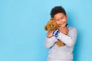 One boy studio isolated on blue wall hugging teddy bear tight