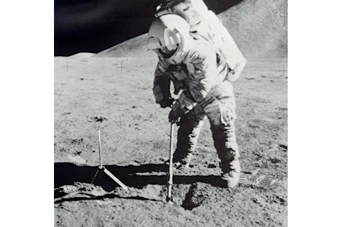 Apollo 15 astronaut uses a scoop to collect soil samples on the moon