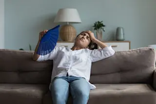 Overheated woman fanning herself on the couch 