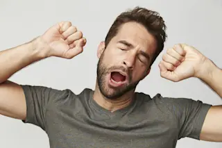 Man streching arms out while yawning with eyes cold