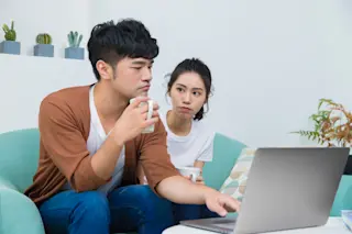 Man working seriously at home and woman looking at him. Woman wishes man accompany her more. Concept of "Love needs much care to grow".