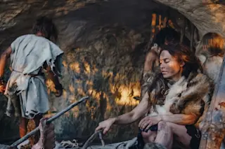 Tribe-of-Hunter-Gatherers-Wearing-Animal-Skin- in-a-Cave-cooking-meat-over-fire
