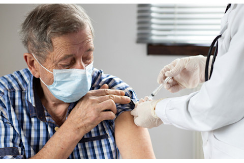 older man with mask getting flu shot