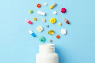 white pill bottle with multiple colorful multivitamins