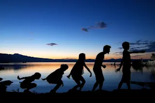 A silhouette image imitating human evolution with blue and orange sunset background