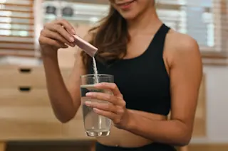 woman putting collagen powder in water