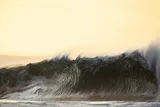 large, dark wave crashing on the beach 