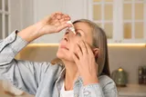 Woman putting in eye drops 