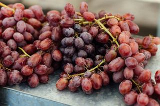 A bunch of grapes sitting on top of a metal table.