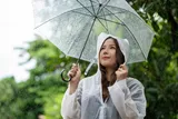 woman in clear rain coat holding clear umbrella in the rain