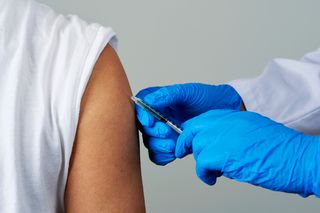 gloved hand administering a vaccine