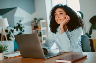 A woman sitting at her desk day dreaming 