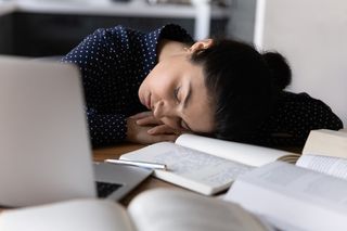 tired woman laying her head on a desk sleeping 