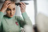Young woman shaving hair before chemo