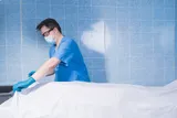 Coroner inspects body with mask on for death smell