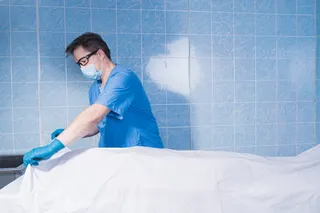 Coroner inspects body with mask on for death smell Coroner inspects body with mask on for death smell