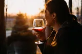 woman watching the sunset and drinking red wine 