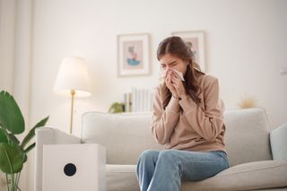 Woman sneezing from poor indoor air quality Woman sneezing from poor indoor air quality
