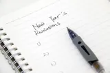 notebook with new years resolutions written at the top, followed by a numbered list and pen. 