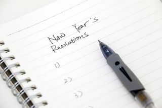 notebook with new years resolutions written at the top, followed by a numbered list and pen. 