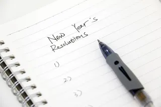 notebook with new years resolutions written at the top, followed by a numbered list and pen. 