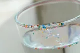 colorful microplastics on a clear glass cup of water