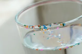 colorful microplastics on a clear glass cup of water