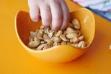 child's hands reaching into dish for peanuts