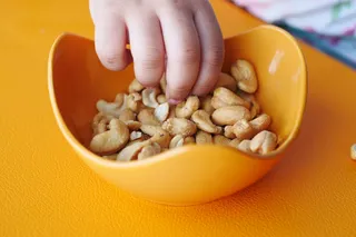 child's hands reaching into dish for peanuts