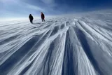 two scientists in winter gear walking on the Prudhoe Dome of Greenland's Ice Sheet.