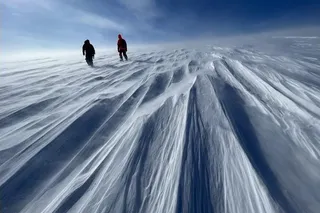 two scientists in winter gear walking on the Prudhoe Dome of Greenland's Ice Sheet.