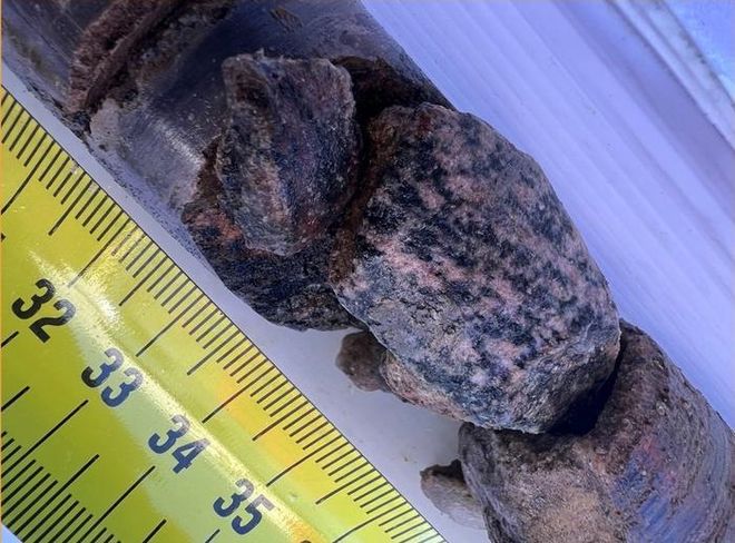 rocks and sediment from Greenland next to a yellow tape measure