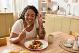 woman sitting at a kitchen table eating food 