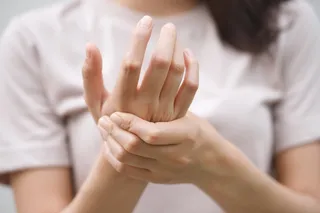 Person holding hand, indicating inflammation in joints Person holding hand, indicating inflammation in joints
